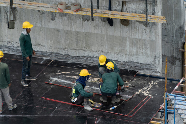 Aerial view of busy industrial construction site workers with cranes working. Top view of development high rise architecture building at noon